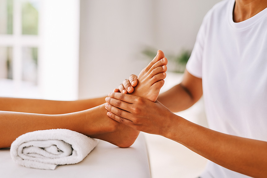 A therapist performing a foot massage in a bright, modern spa setting.