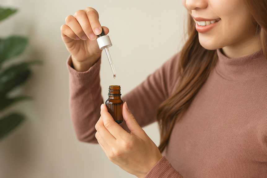 Woman using dropper with amber bottle.