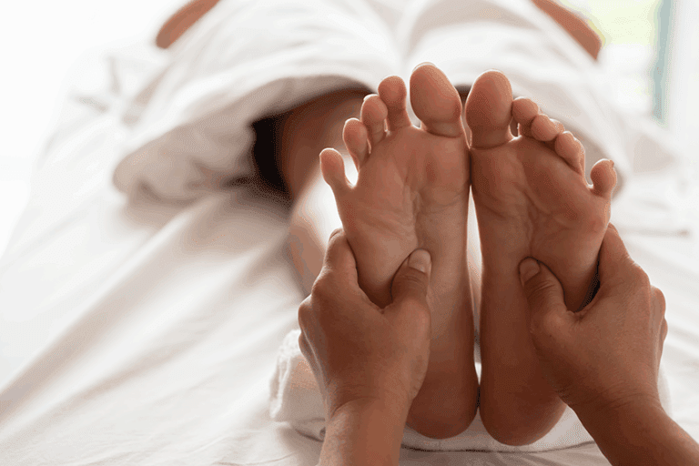 Close-up of a therapist pressing reflexology points on the feet during a wellness treatment, a practice used for relaxation rather than diagnosing illness.