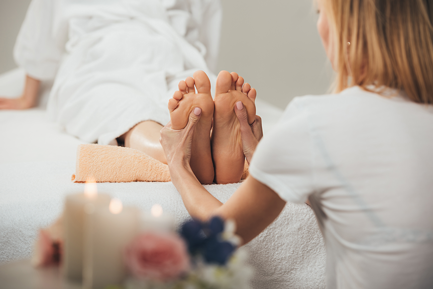 Therapist performing reflexology on pregnant woman’s feet to encourage labour