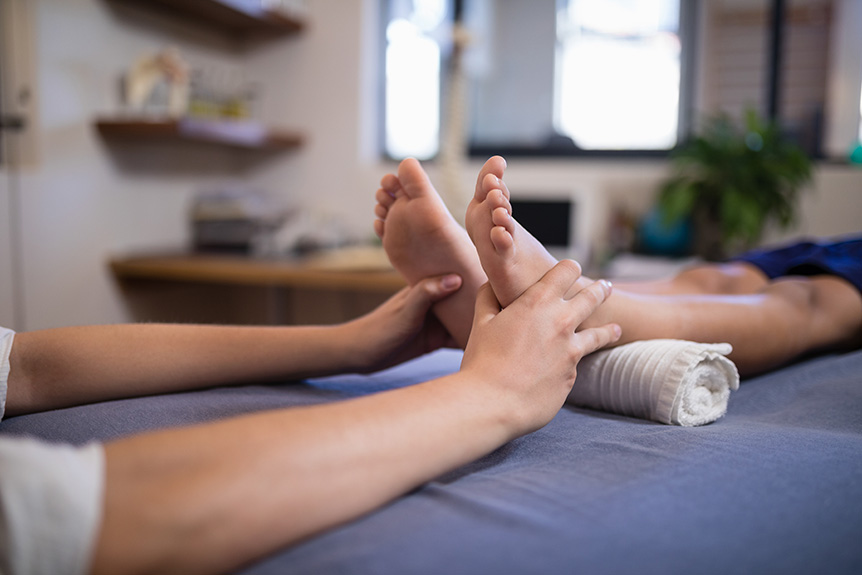 Therapist performing reflexology on sore foot for pain relief