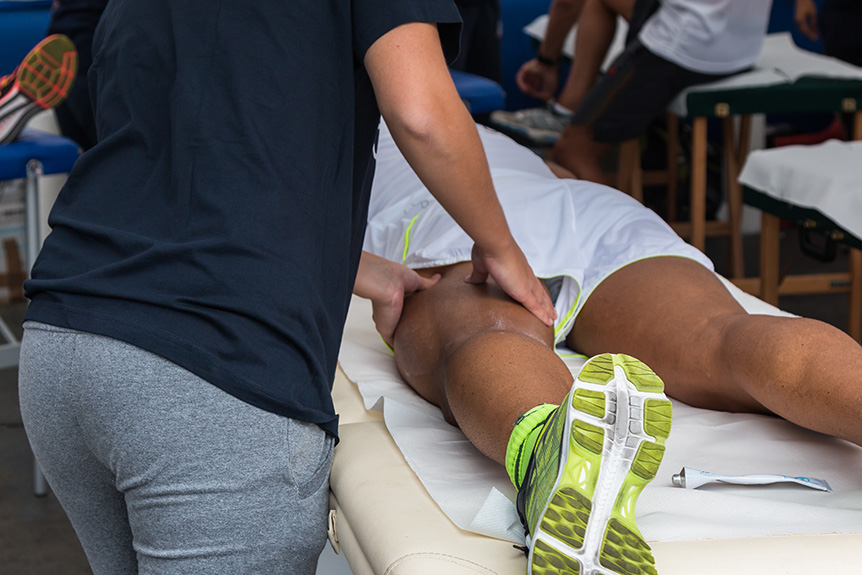 Sports therapist massaging an athlete’s leg muscles to aid recovery and comfort, a practice unrelated to illness detection.