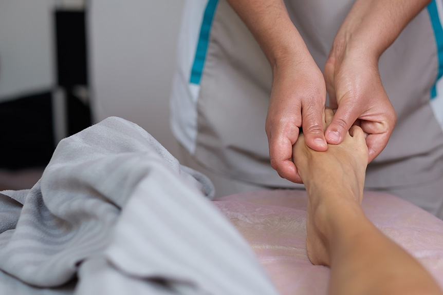 Close-up of a reflexology practitioner applying pressure to foot reflex points during a session that may cause mild, temporary reactions in some people.