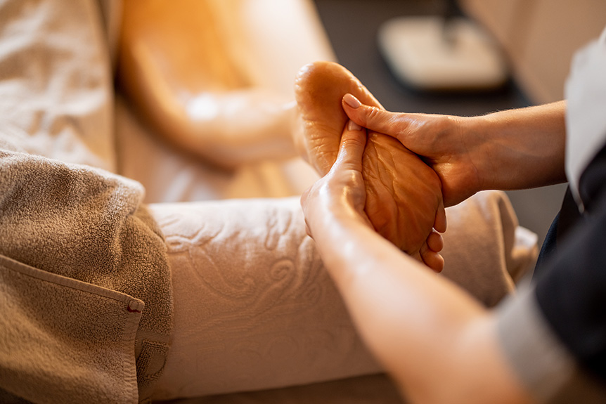 Therapist using light pressure on the foot during a reflexology session designed for clients with diabetes.