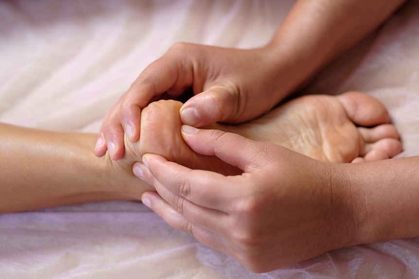 Reflexology practitioner working on foot pressure points during a session where some people may experience brief, mild after-effects.