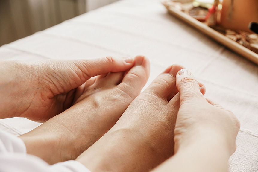 Individual massaging their own foot and pressing reflex points as part of a simple self-reflexology routine.
