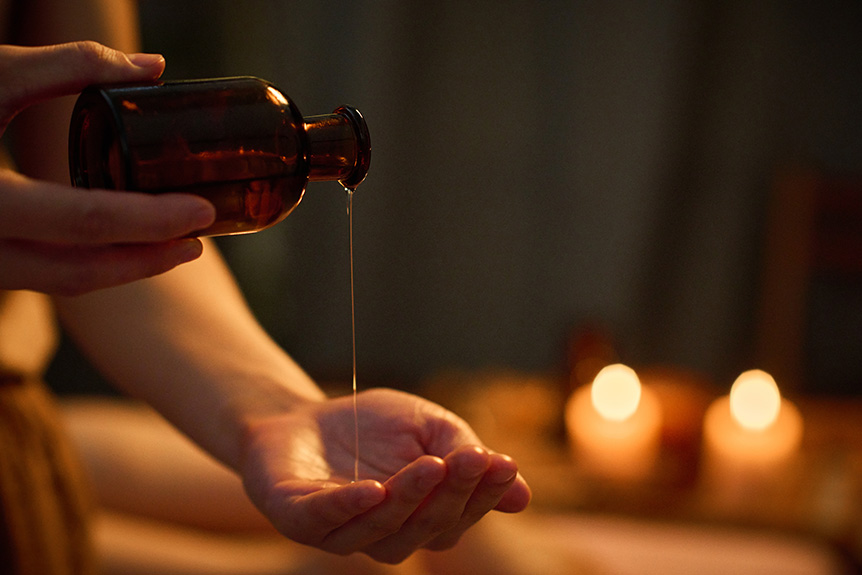 Massage therapist pouring essential oil into their hands before a massage to improve relaxation, mood, and overall massage effectiveness.