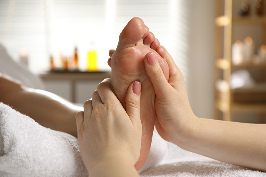 Reflexology practitioner applying gentle pressure to the sole of the foot during a foot reflexology session often discussed as part of holistic wellness routines.