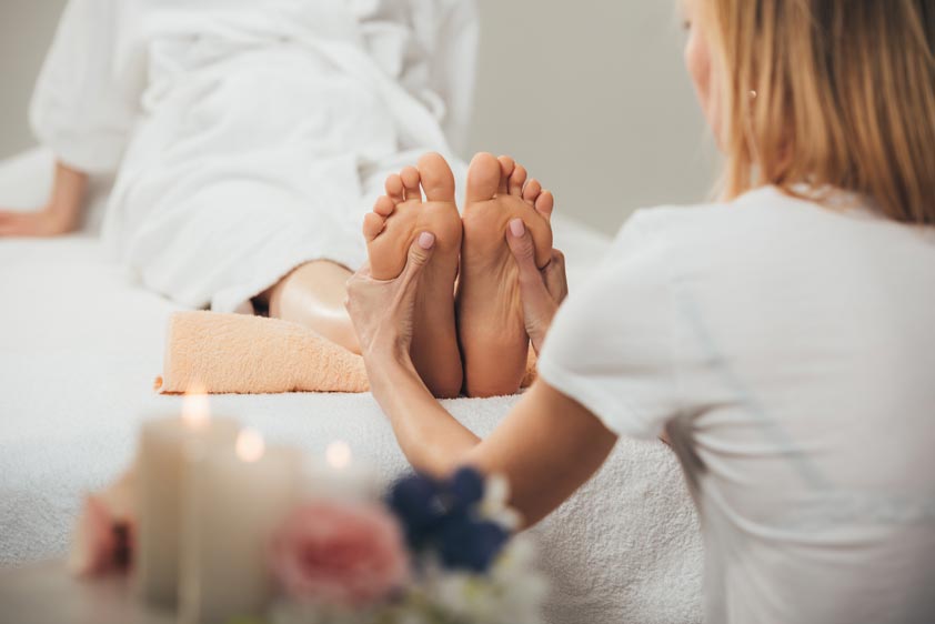 masseur doing foot massage to adult woman in spa