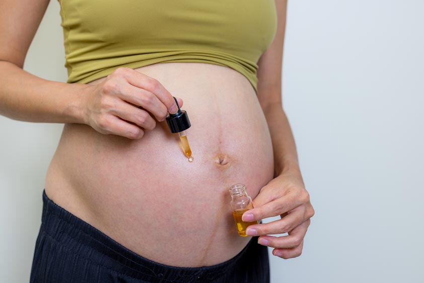 Pregnant woman apply oil on her tummy