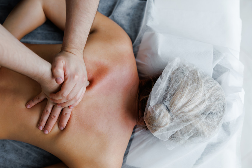 Therapist performing deep tissue back massage on woman