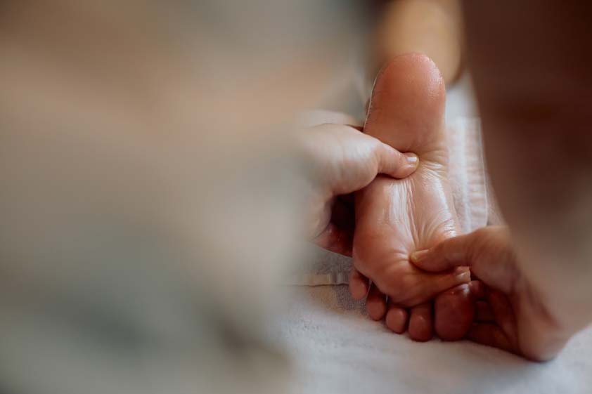 Reflexology session in progress showing therapist applying pressure to feet in a calm spa environment