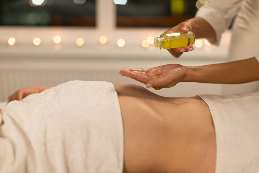 professional masseuse pouring oil on hands for massage