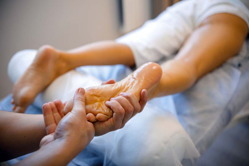 Foot reflexology treatment in a modern spa environment demonstrating safe technique