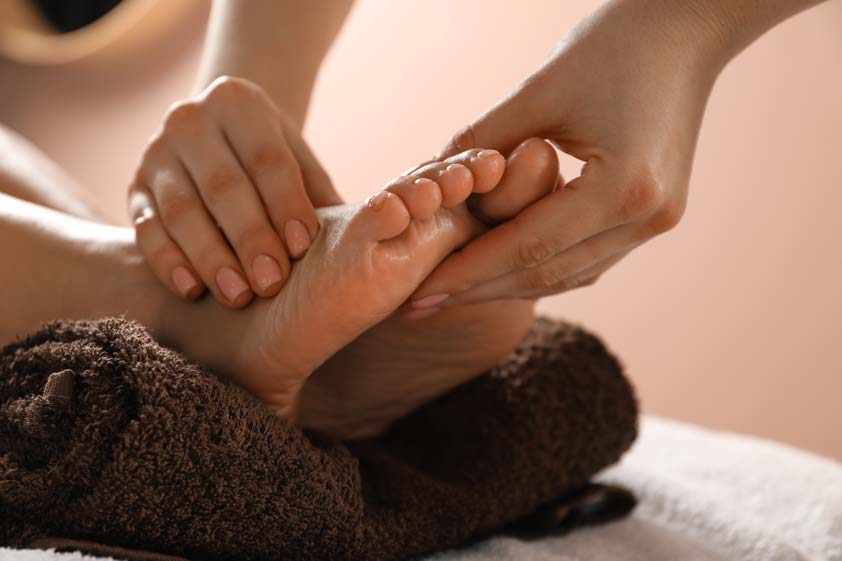 Close-up of therapist performing gentle foot reflexology massage in a spa setting